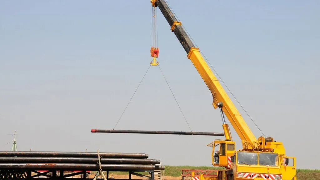 Içamentos: equipamento içando barra de ferro em obra.