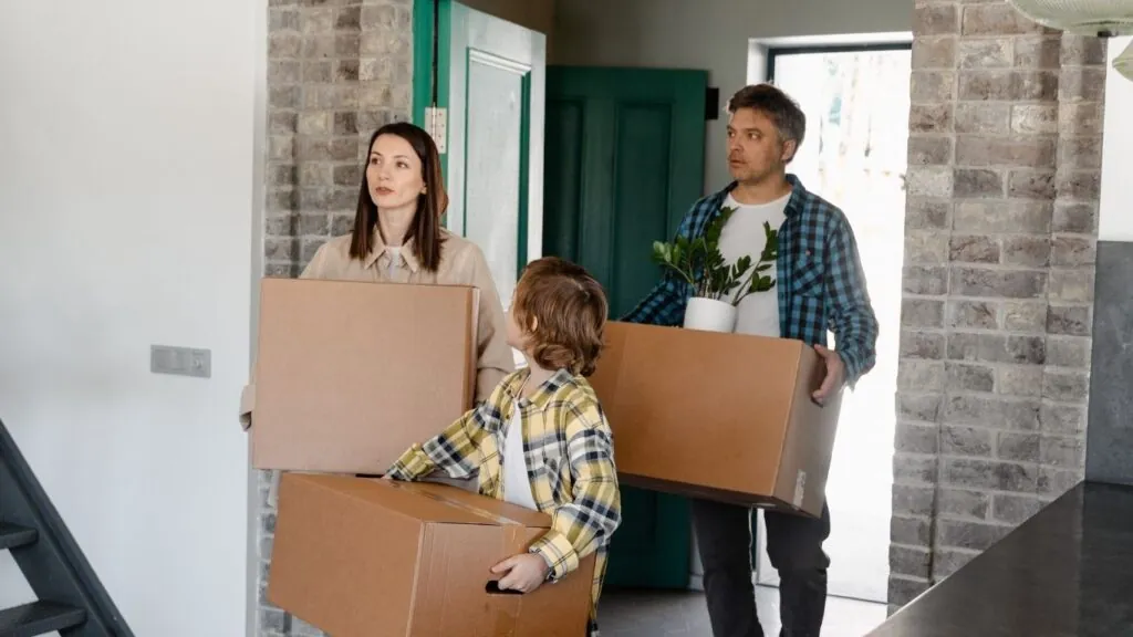 família entrando em casa nova com caixas.