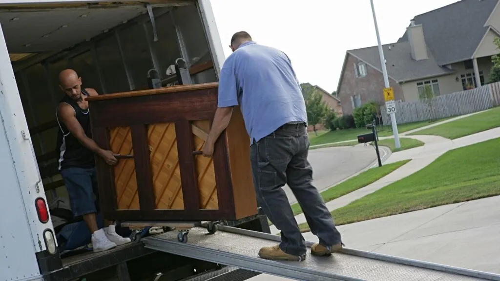 Homens carregando móveis para dentro de caminhão.