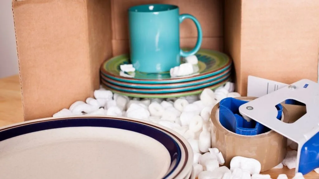 Pratos e xicaras próximo de materiais para embalar.